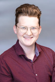 Jo Jones is non-binary, an ECE advisor, and wears a red dress shirt and glasses